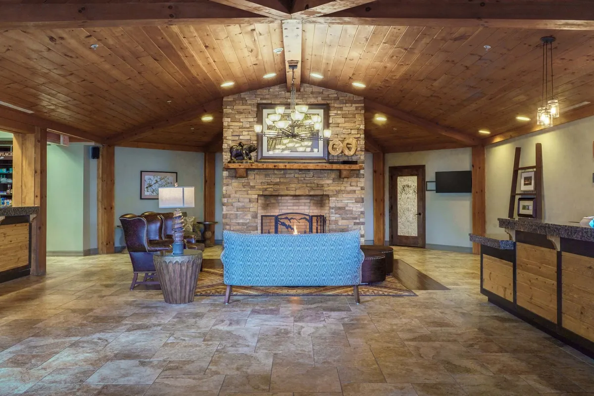 A living area centered around a handsome stone fireplace, with a plush blue couch, exposed wooden beams, and thoughtful decorative touches. The inviting atmosphere makes it ideal for curling up by the fire or sharing stories.