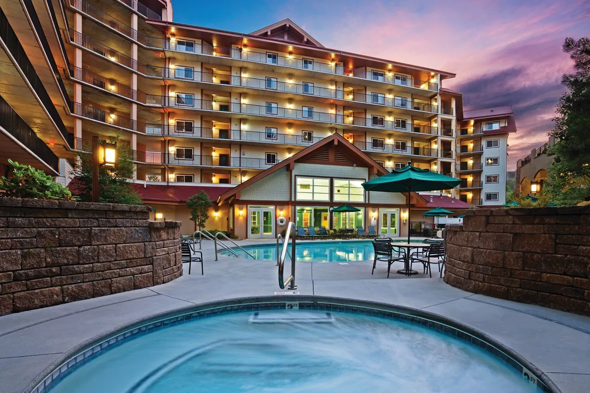 This exterior image captures the resort's pool area with a swimming pool, hot tub, lounge chairs, and hints of building facade and landscaping. The scene subtly nods to the possibility of outdoor meals and socializing, especially with references to evening barbecues and intimate conversations under the stars.